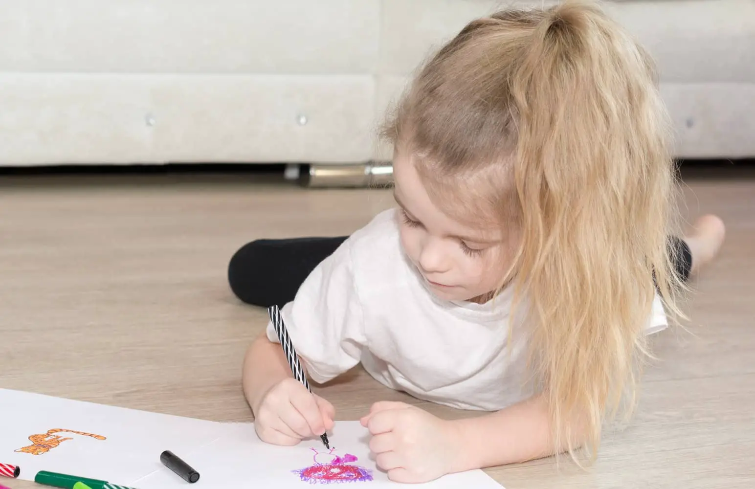girl lying on the floor and colouring in a drawing