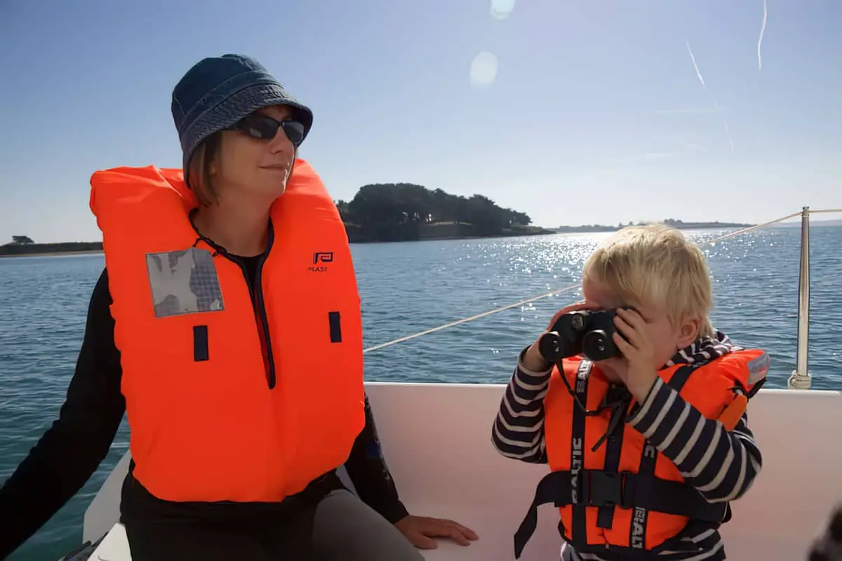 mother and son wearing lifejackets on a boat on the water