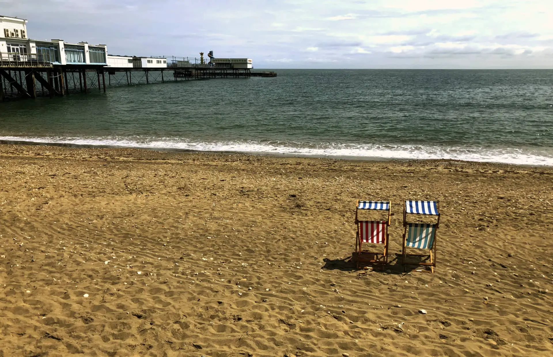 sandown beach with two deckchairs and pier in the background