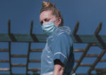 care worker in PPE standing in a garden with blue sky behind
