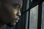 man standing at window looking too anxious about going out
