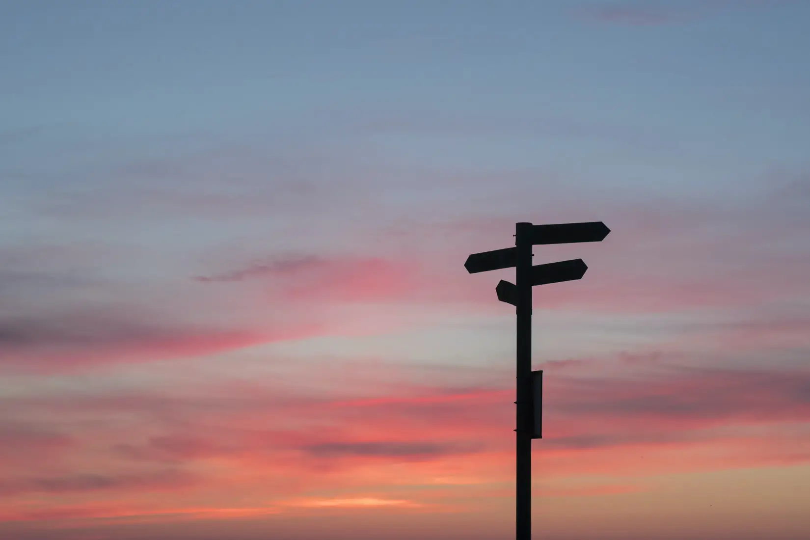 silhouette of sign posts with red sky in background