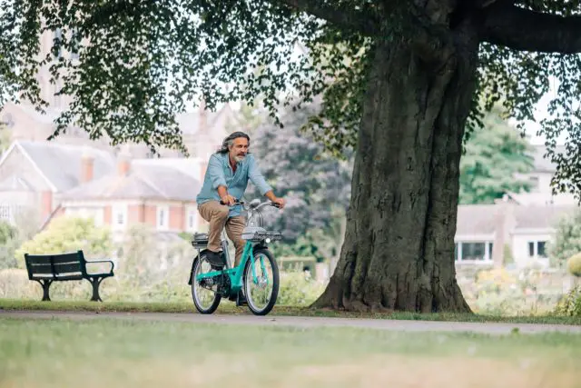 Older man cycling on a e-bike through a park