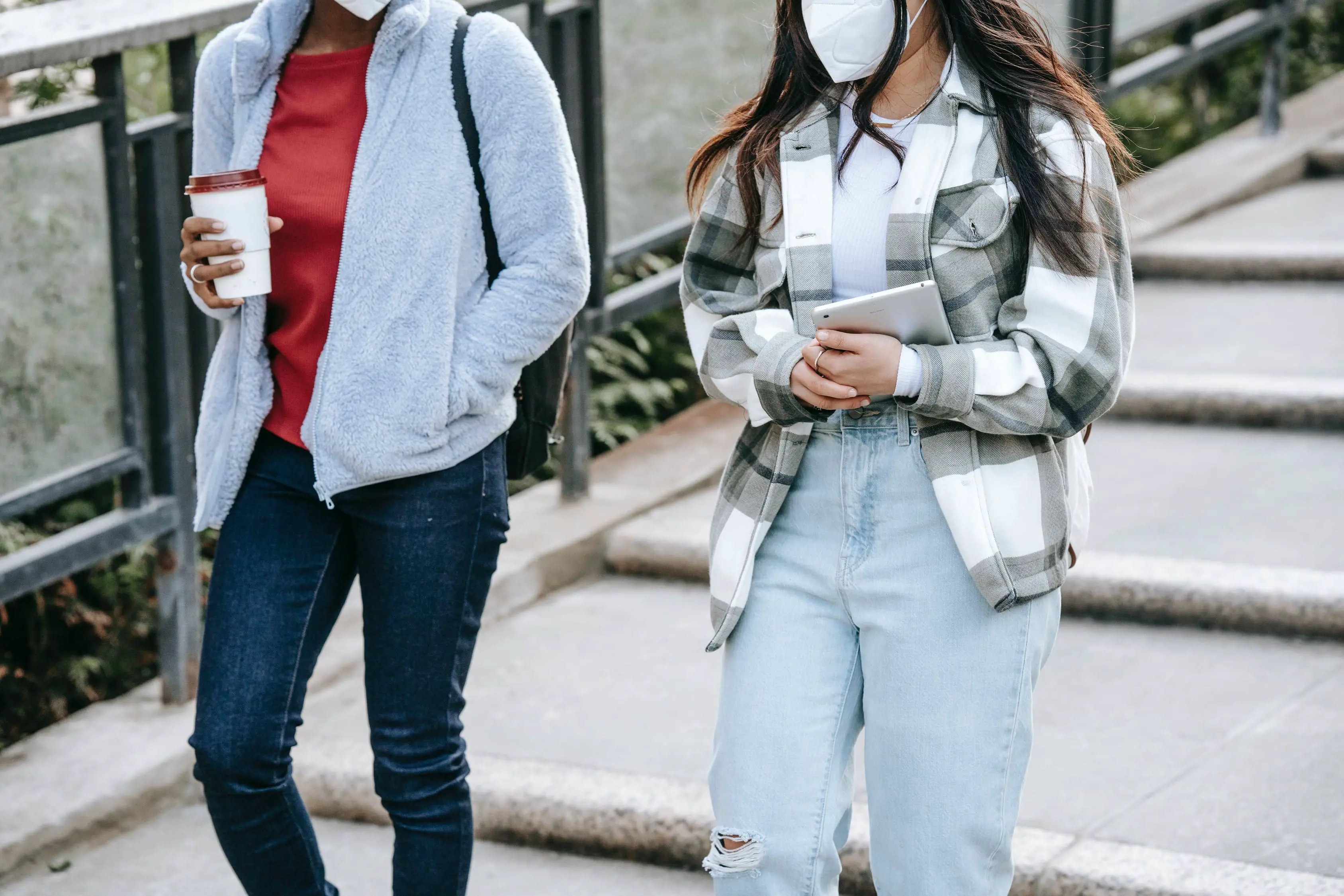 Two teenagers walking down the street wearing face masks