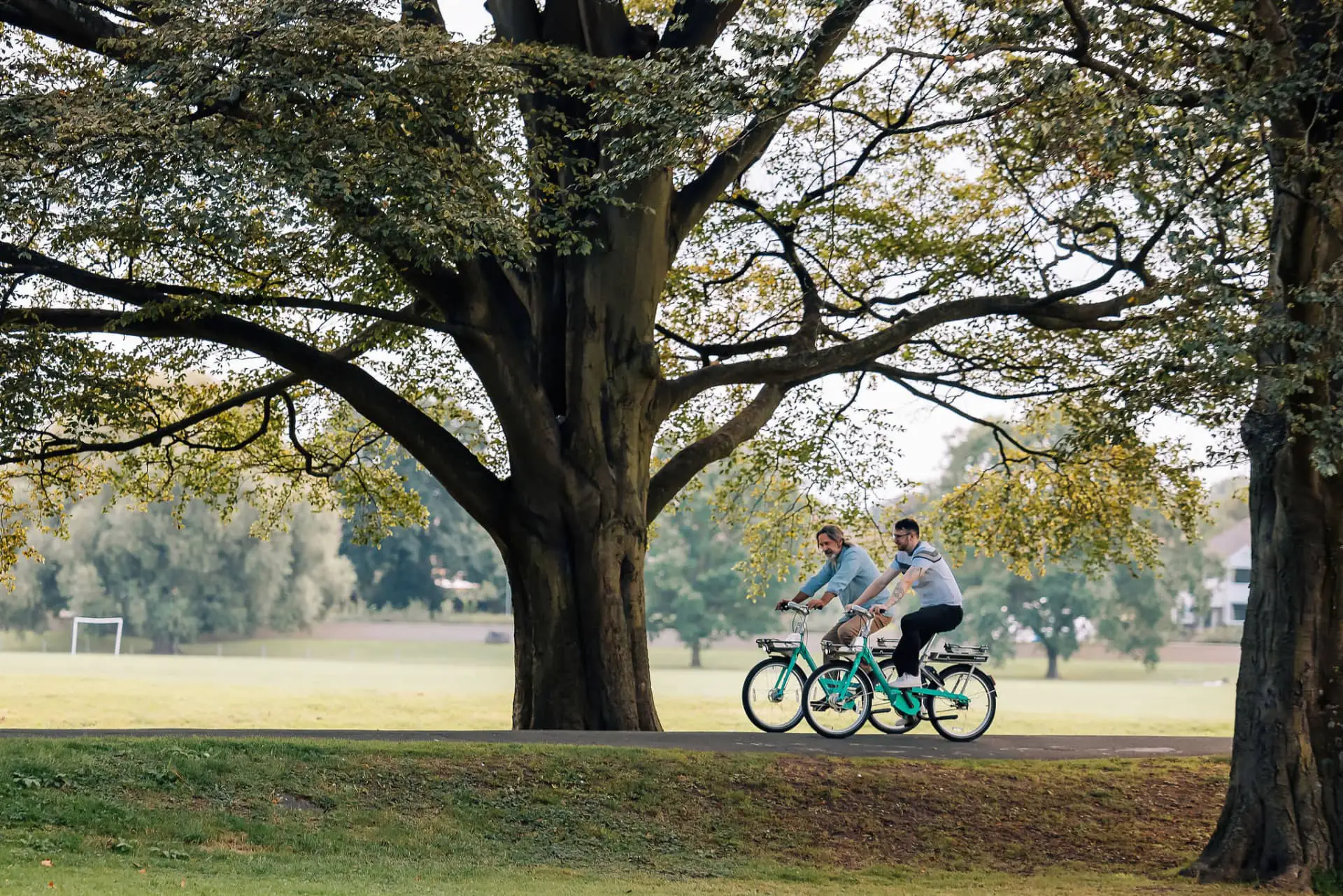 two men riding Beryl electric bikes through a park