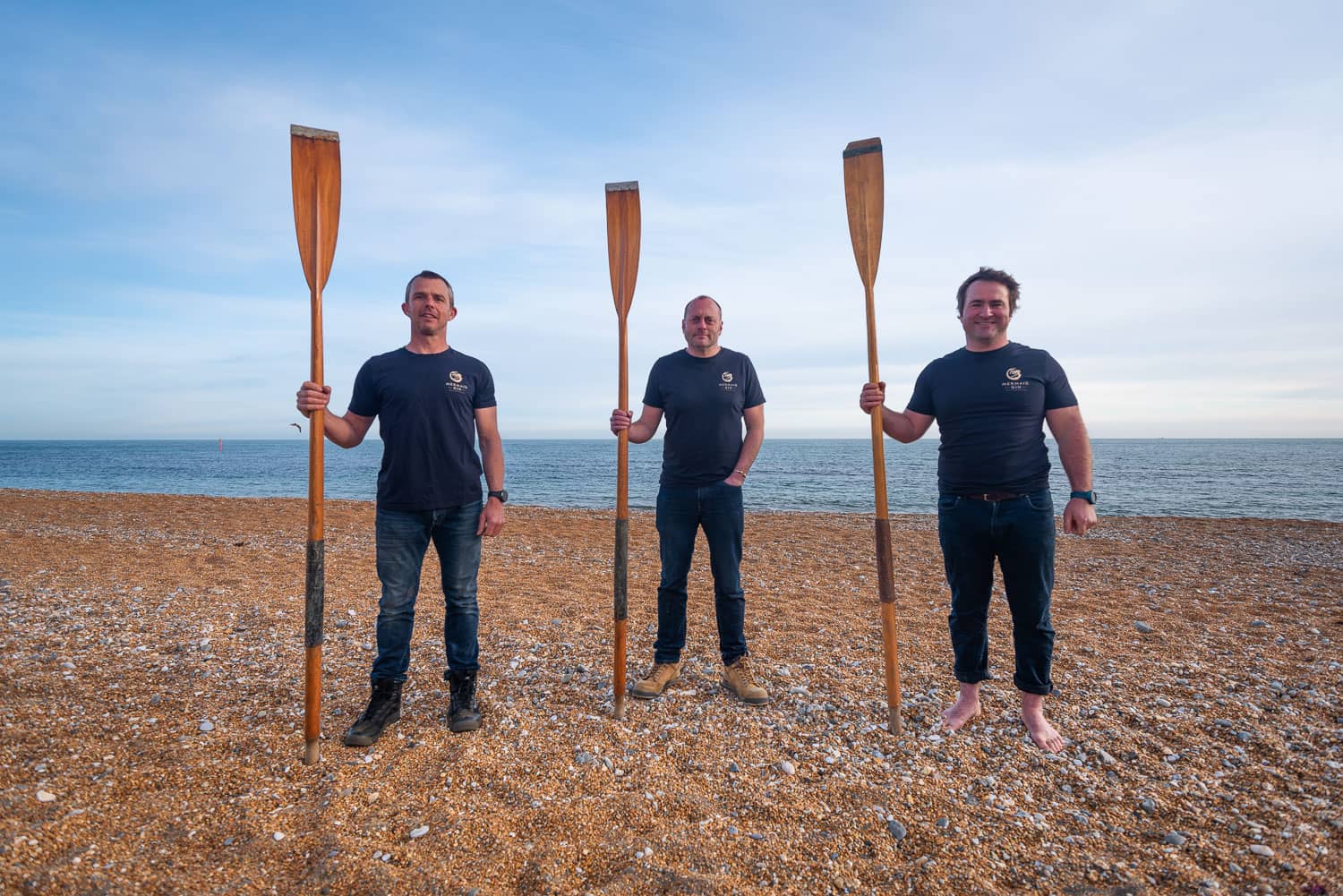 Chris, Xavier and Paul standing on the beach with oars in their hands