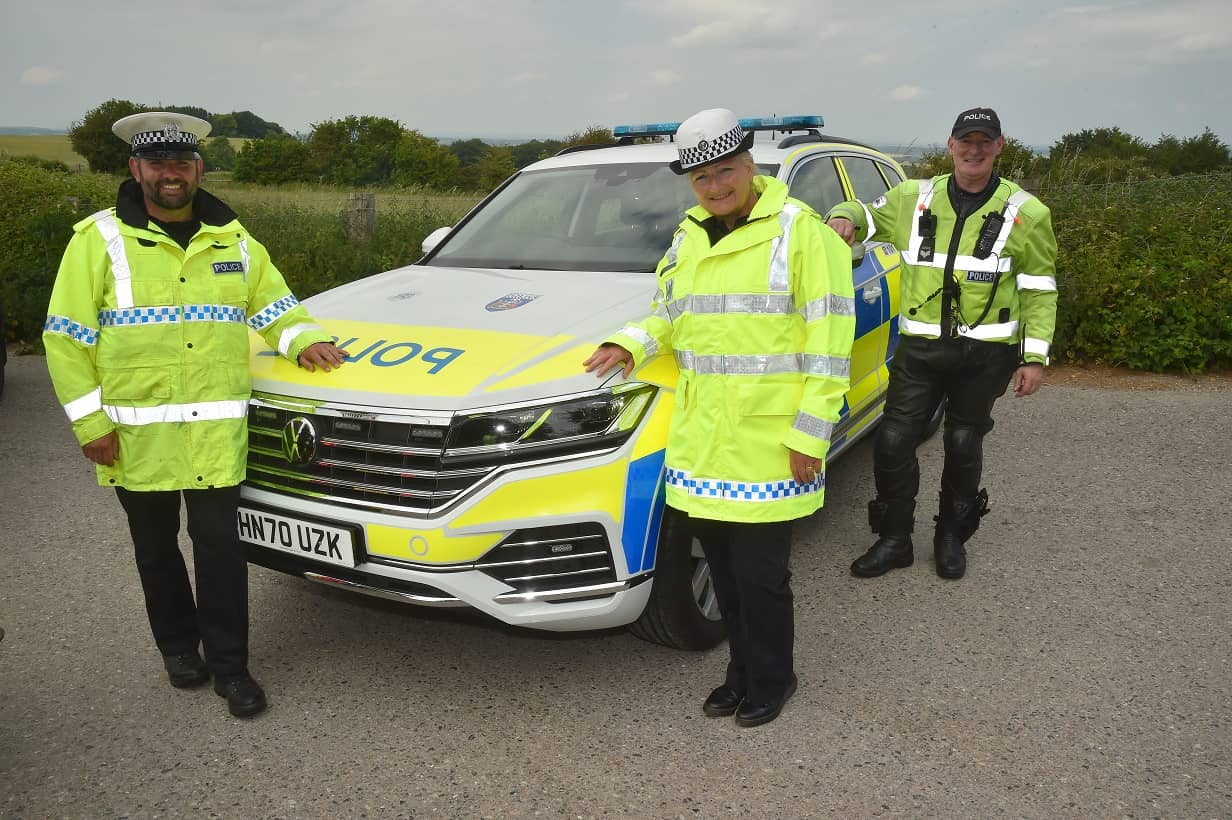 Three members of the Roads Policing Unit standing by car
