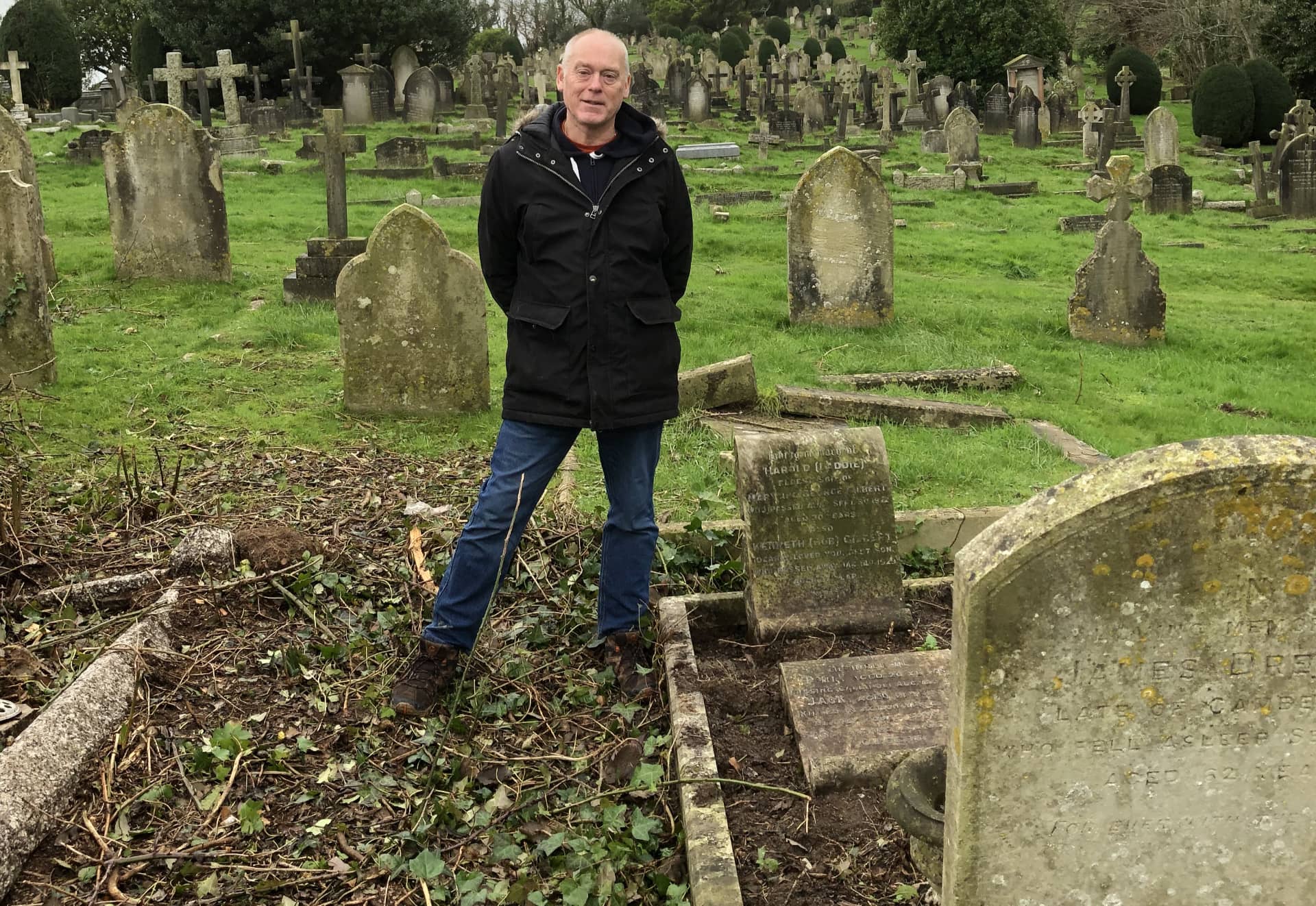 Mark Jeffries next to the grave that was hidden before by overgrowth