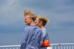Two people on a windy ferry with their hair flying high