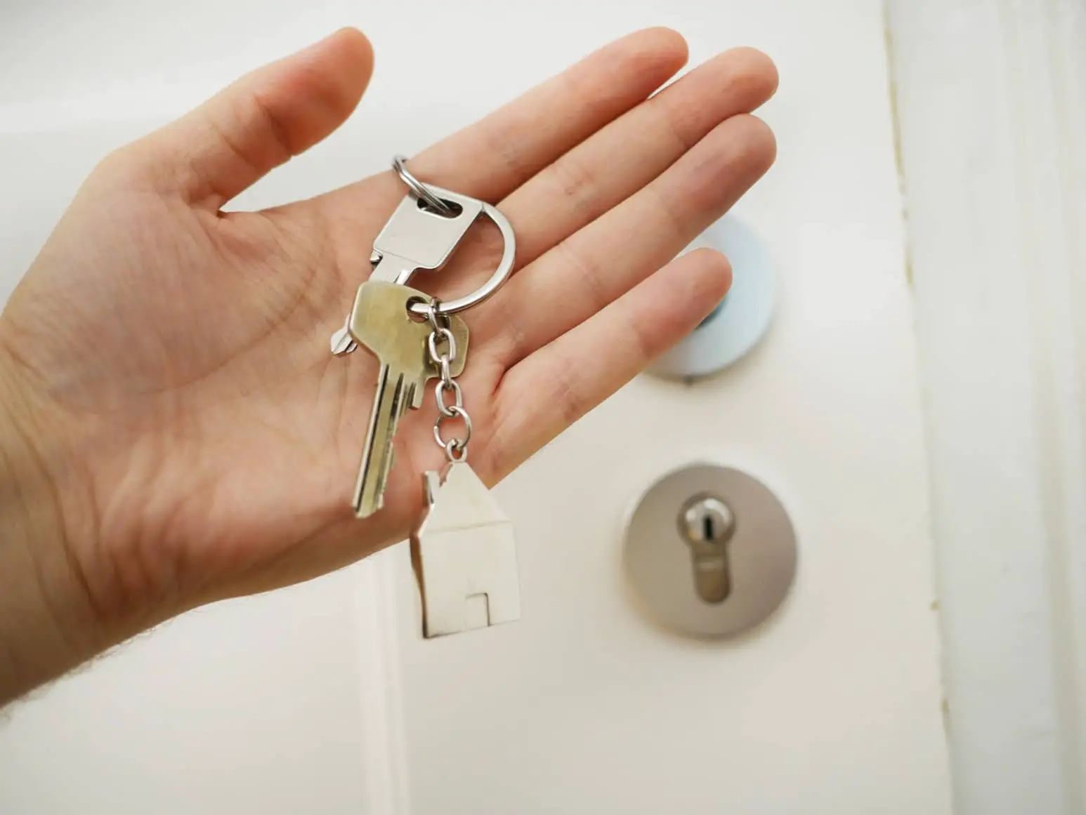 person holding door keys and standing by door
