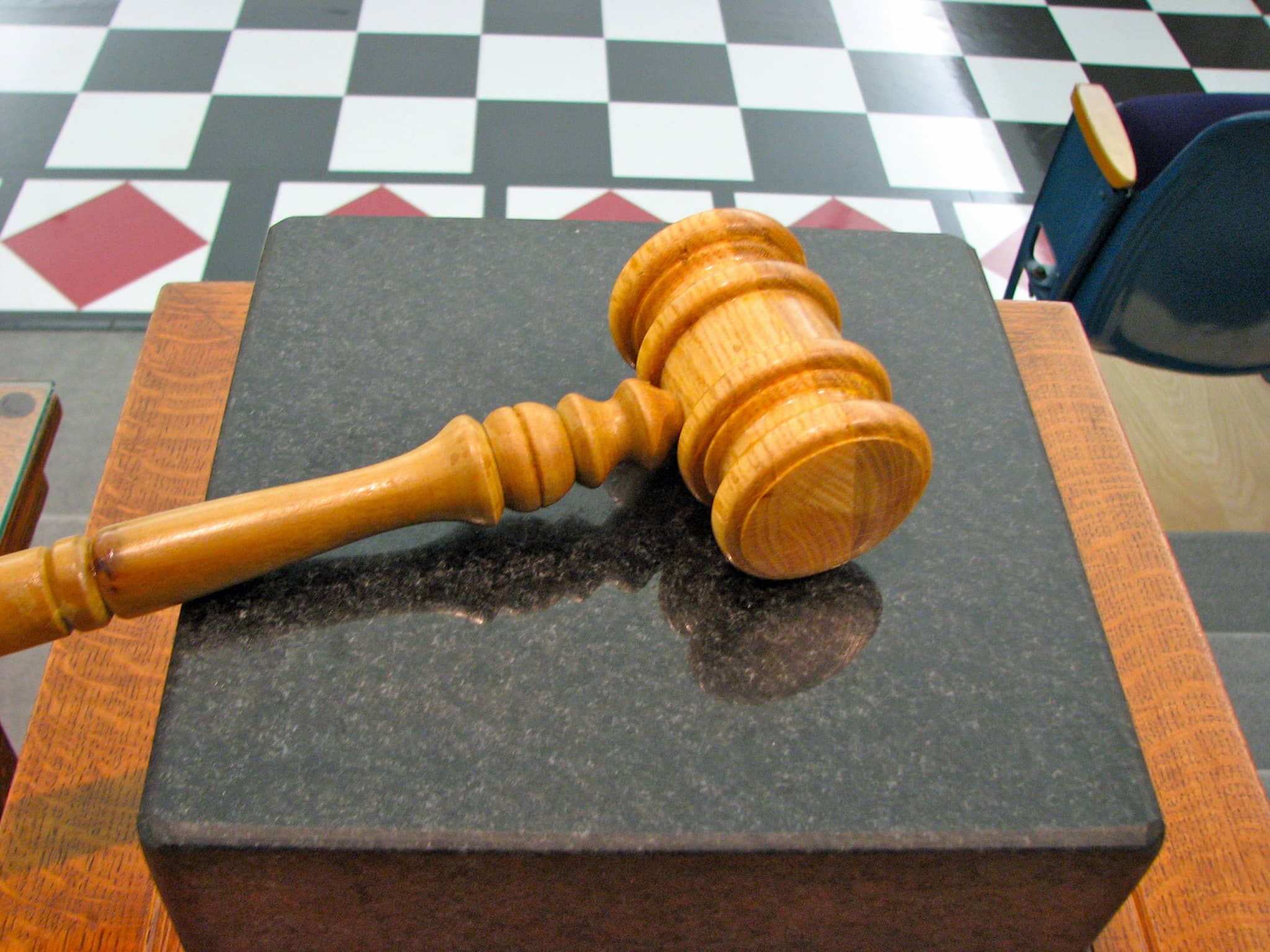 Gavel on marble block with tiled floor in background