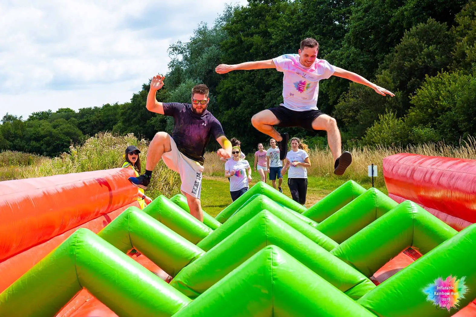Two men on the Rainbow Run inflatable bouncing high