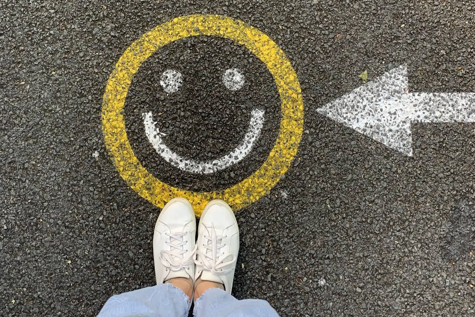 someone standing by a smiley that is painted onto the road