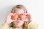 Girl holding eggs over her eyes