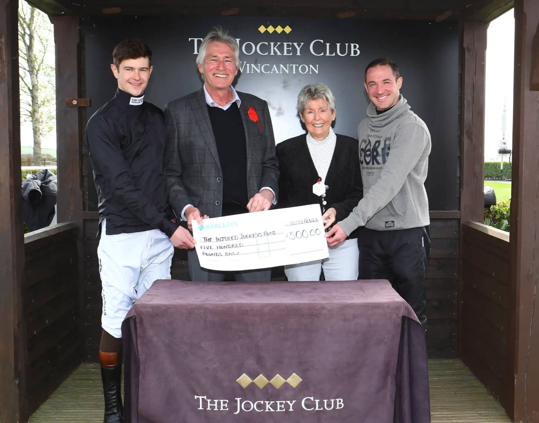 Phil and June Sherring (centre) present Wightlink’s cheque to jockeys Brendan Powell and Richie McLernon, representing the Injured Jockeys Fund at Wincanton racecourse