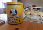 Old fashioned baby milk tin with old photo and teddy in the background -