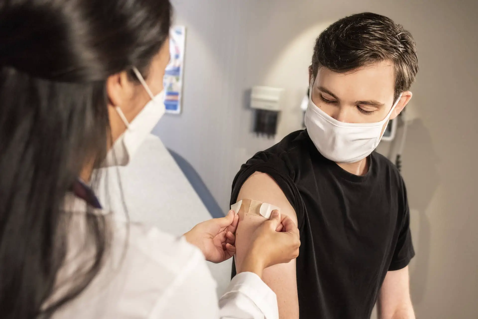 Young man having plaster applied after being vaccinated - by CDC
