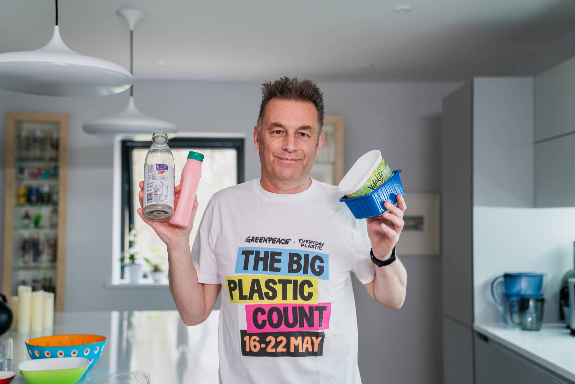 Chris Packham holding plastic containers in a kitchen