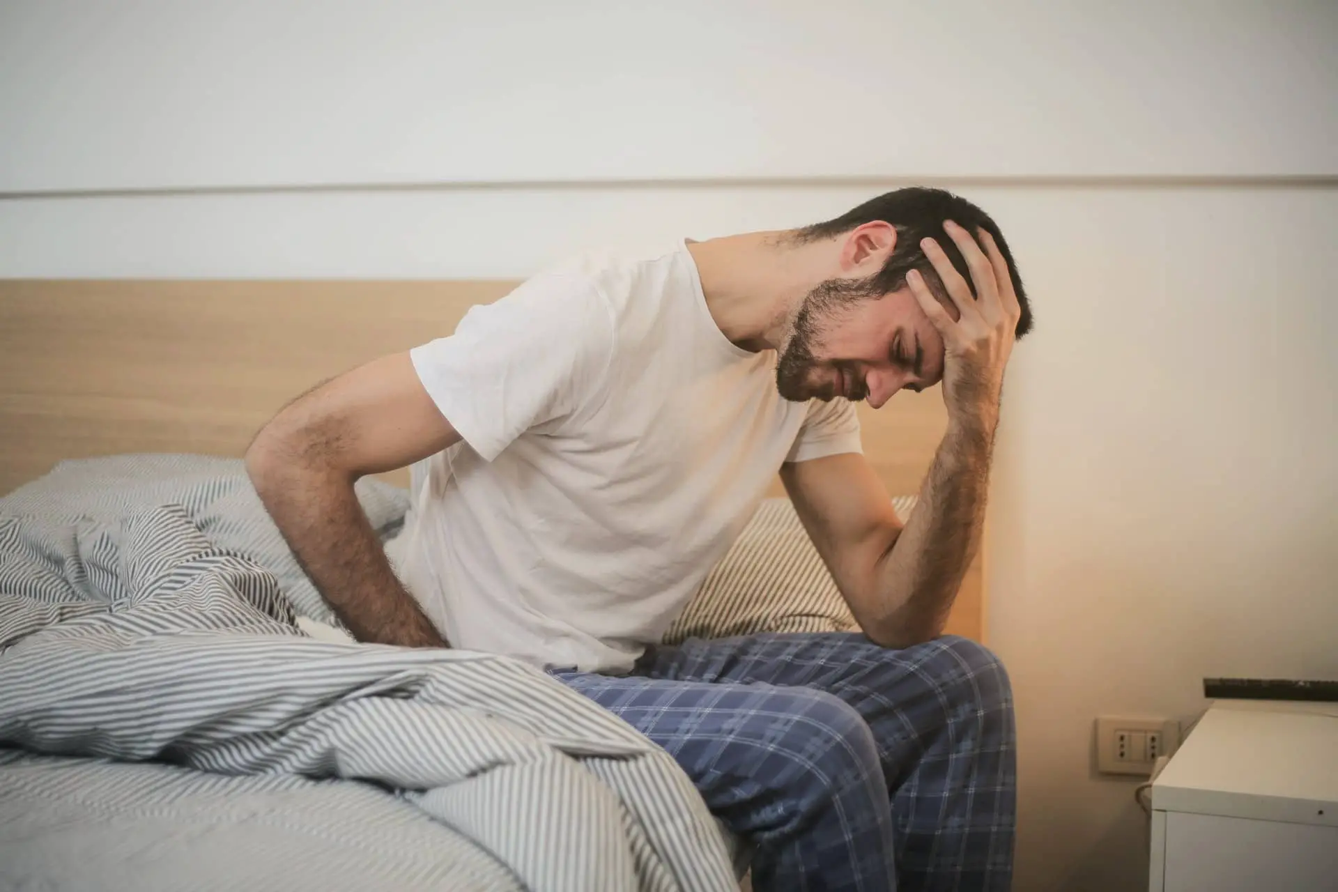 Man sat on bed looking exhausted