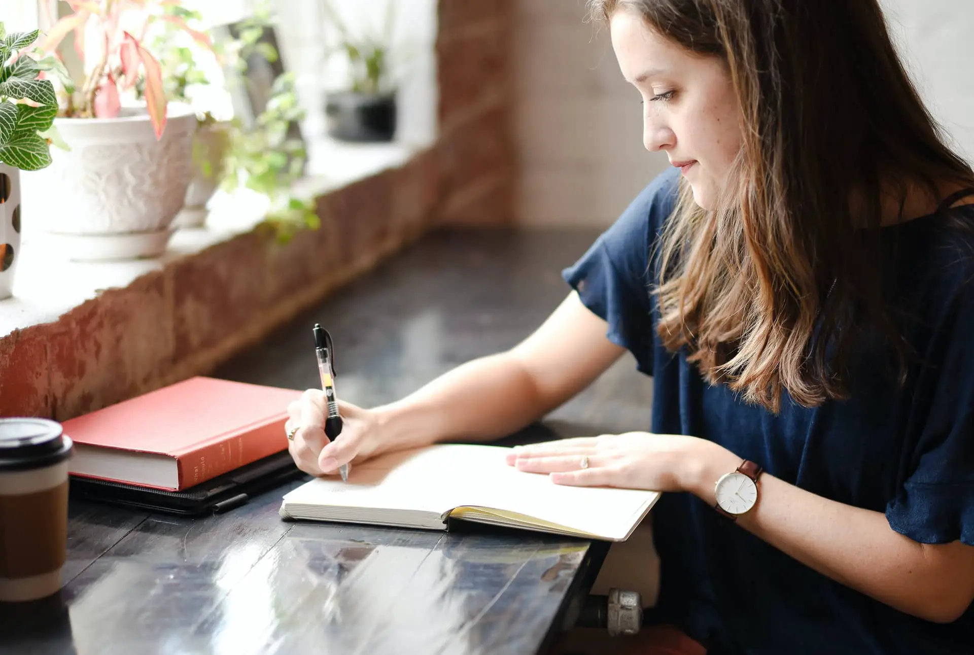 Woman sat at desk writing in notebook