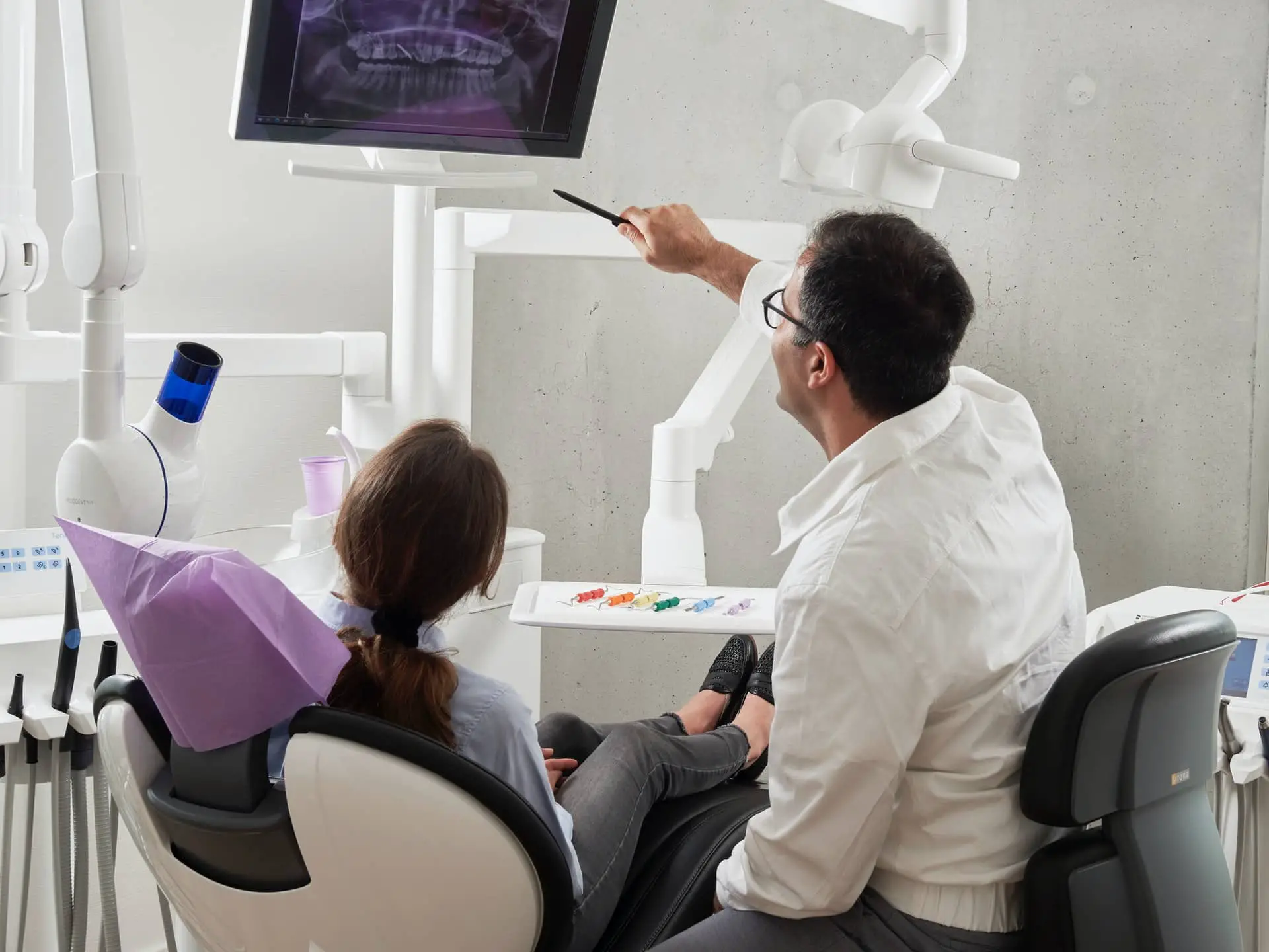 person in dentists chair with dentist explaining xray