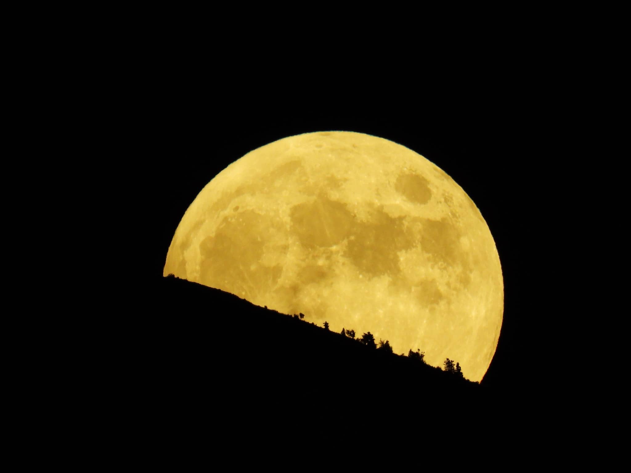 Full moon behind side of hill