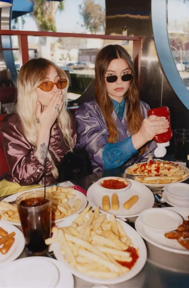 Hester and Rhian sitting in a diner with plates of fries in front of them