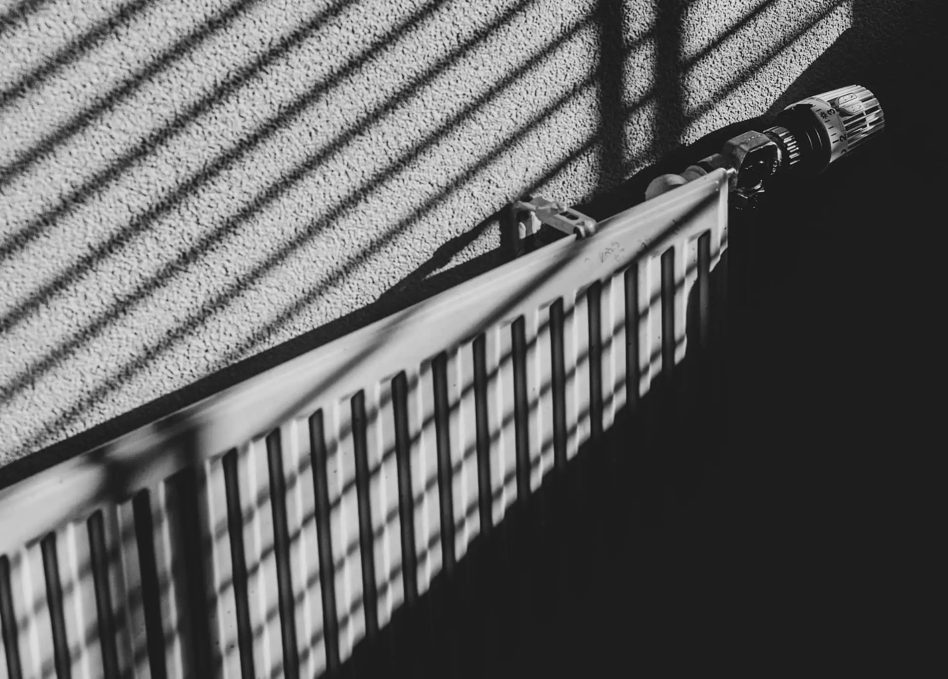 Black and white image of a radiator with shadow of blinds