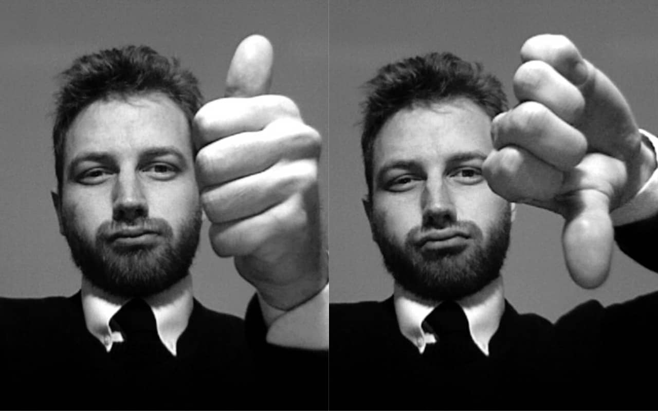 A man in a suit giving a Thumbs Up and a Thumbs Down gesture