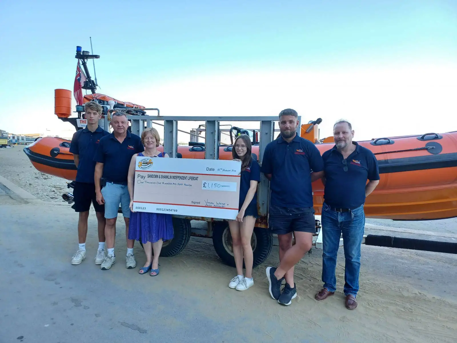 Vivien and Emilia presenting cheque to Lifeboat volunteers