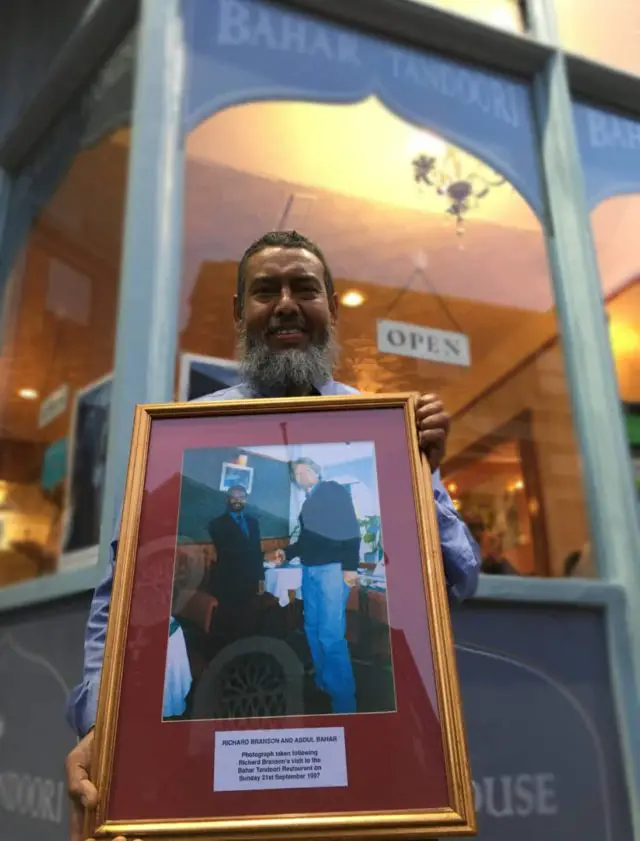 Abdul Bahar outside the restaurant with photo of him and Sir Richard