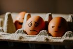Box of eggs with faces drawn on including a worried one