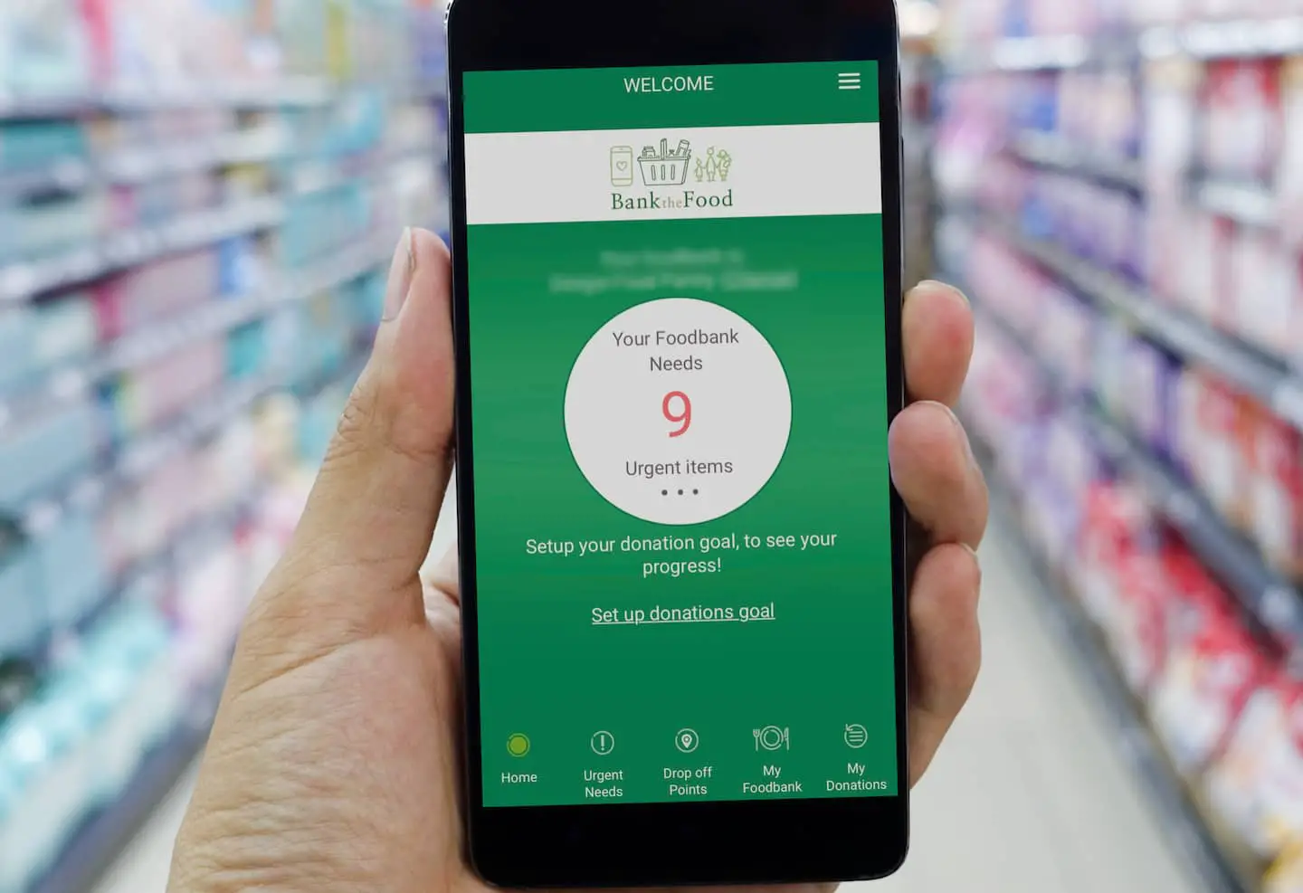 Person holding a mobile phone in supermarket with BanktheFood app open