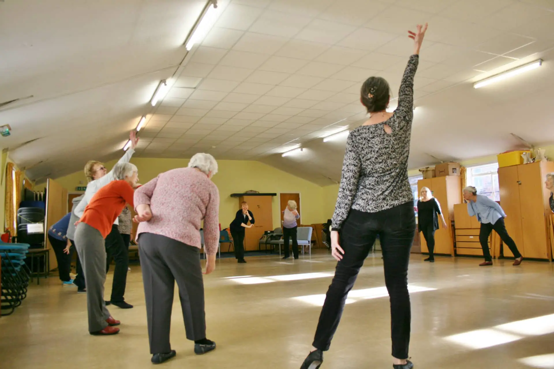 Older women taking part in dance sense classes by stretching
