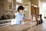 child washing their hands in large domestic kitchen