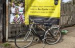 Re-cycled bicycle in front of banner promoting the scheme