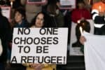 Protester with sign reading no-one chooses to be a refugee