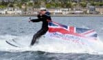 Navy serviceman on water skis with Armed Forces Day flag flying behind him