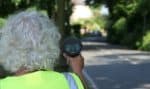 Person pointing a speeding device at the road as part of Community Speedwatch scheme