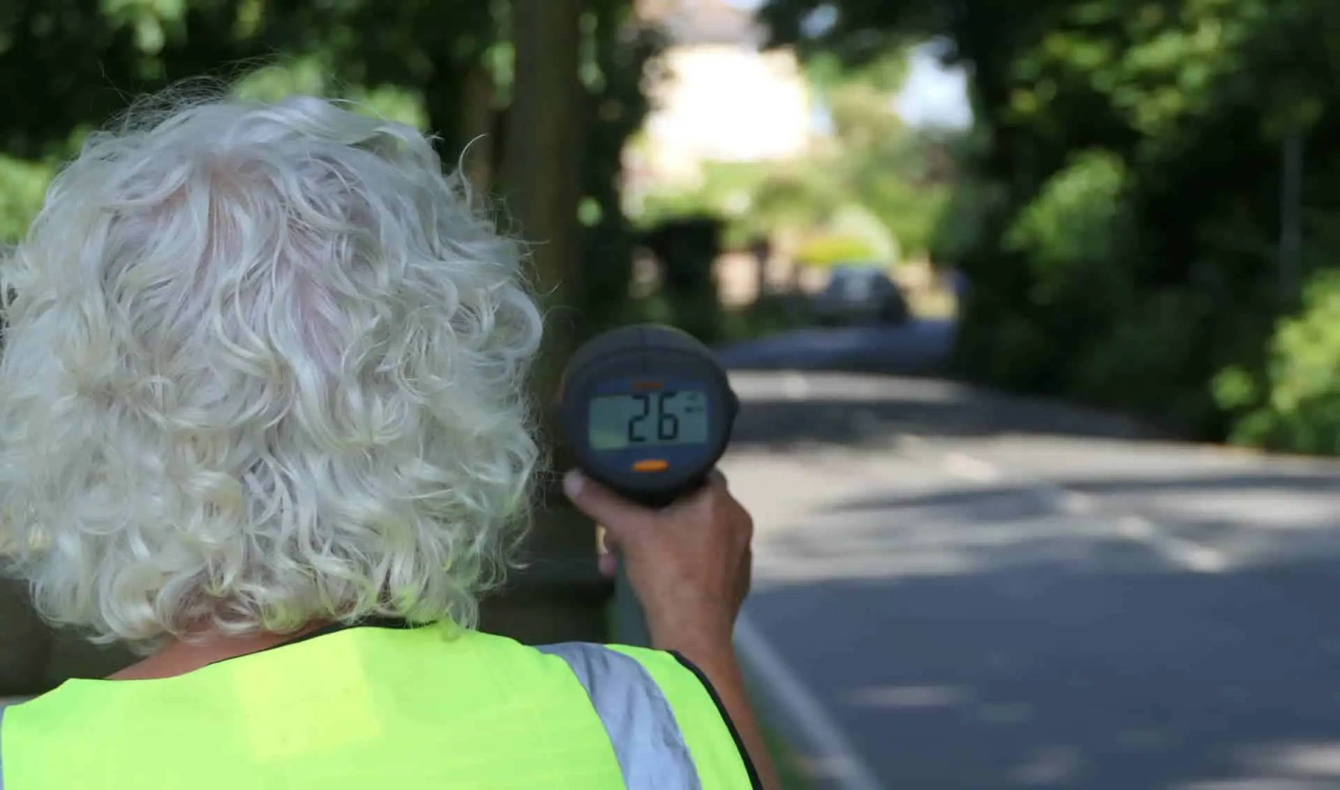 Person pointing a speeding device at the road as part of Community Speedwatch scheme