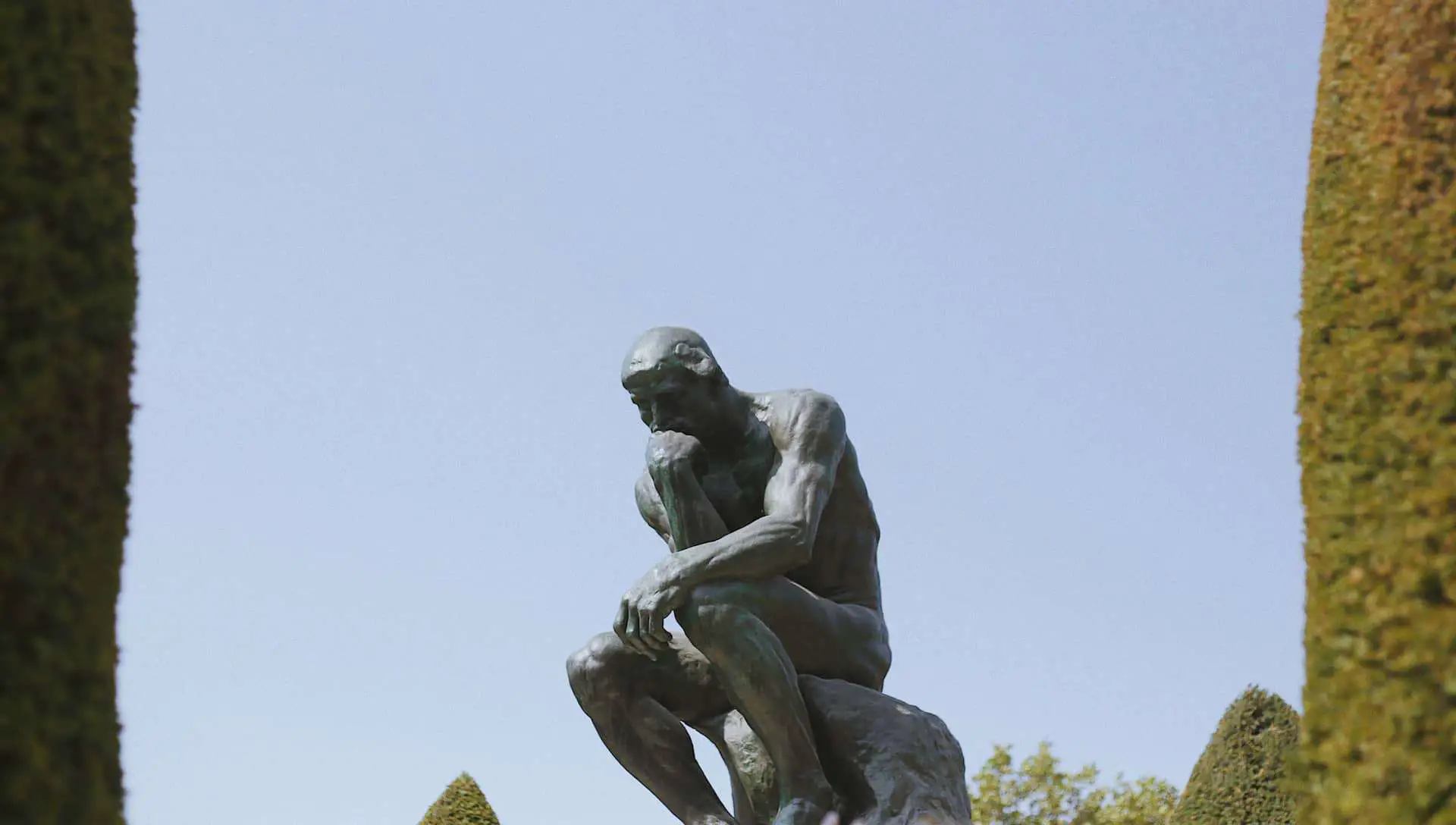 The thinker statue in a manicured garden