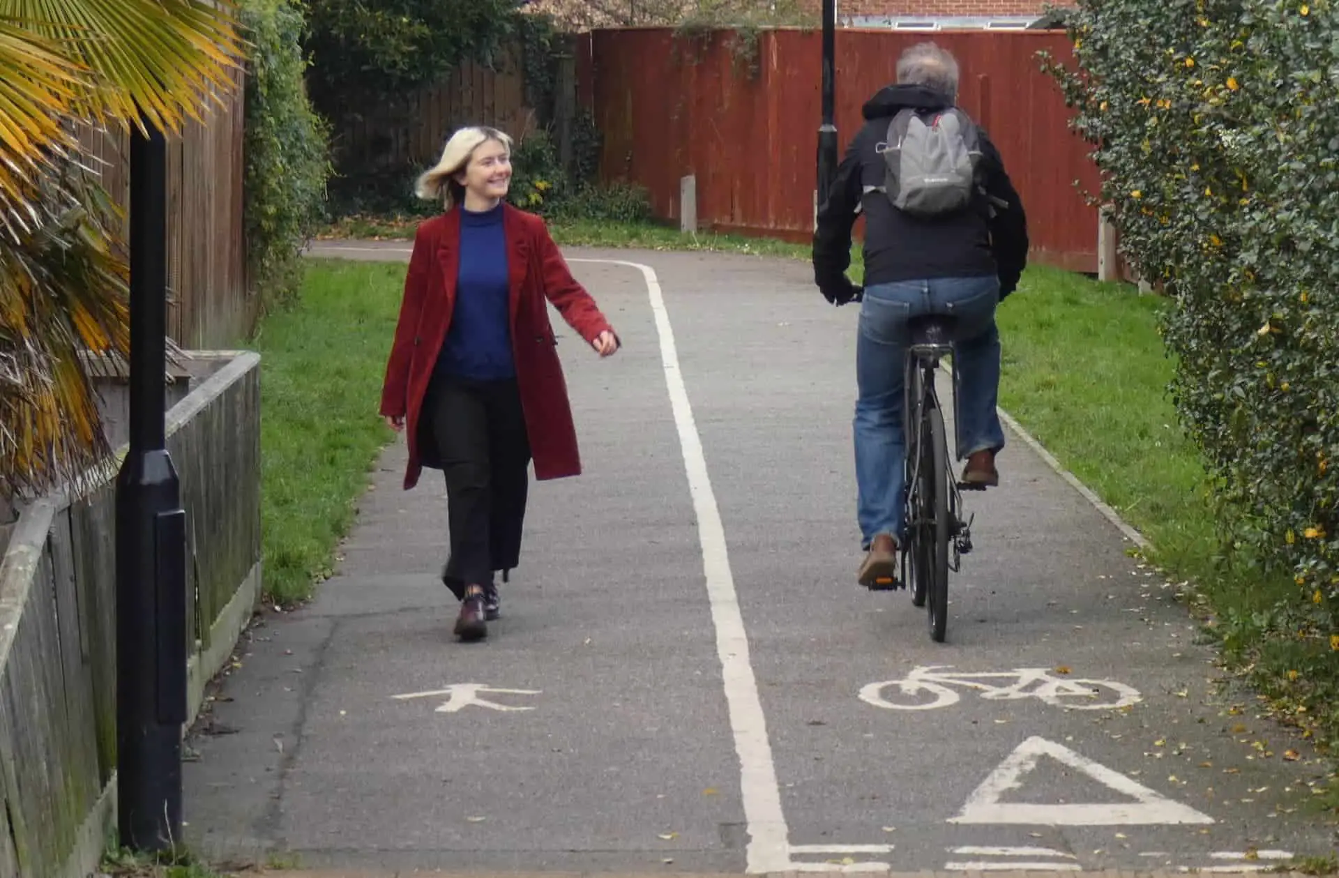 Woman walking on footpath and cyclist in cycle lane