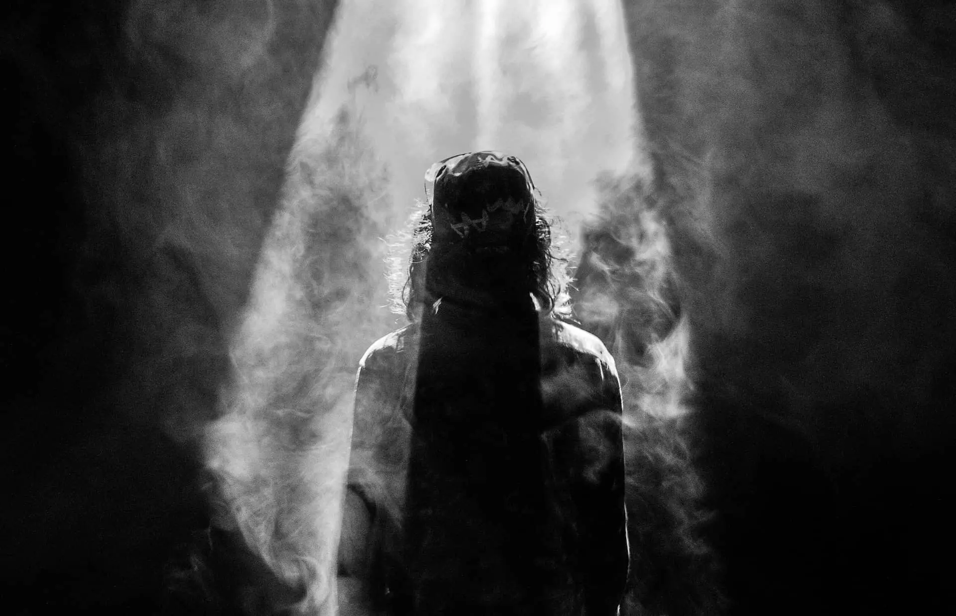 man standing under light with mist around him
