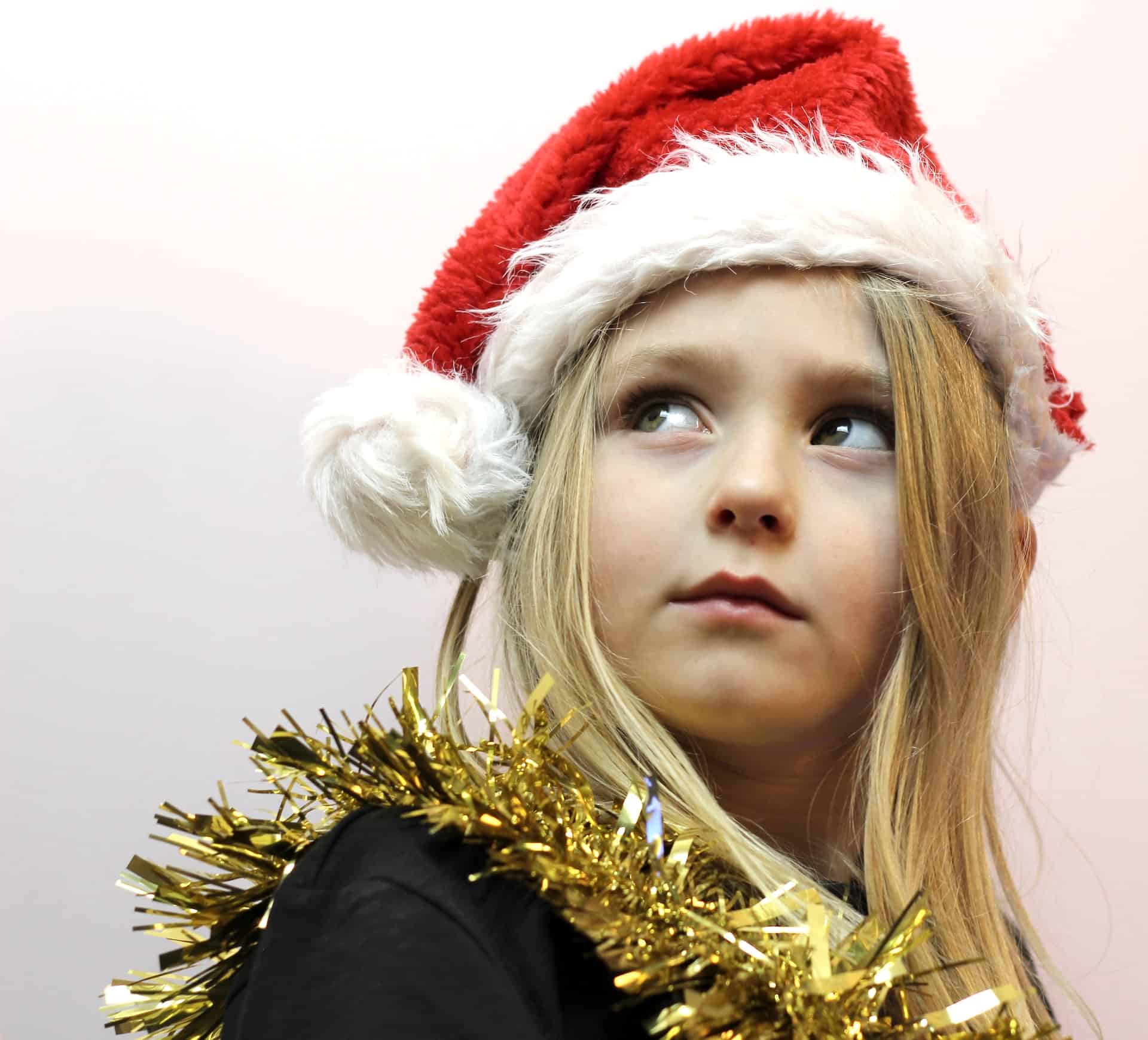 child with xmas hat and tinsel on looking to the sky