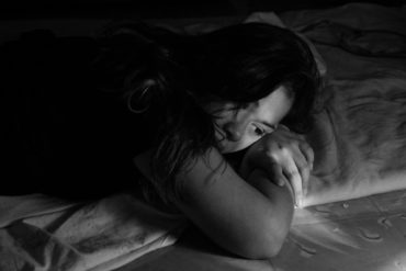 girl looking unhappy in bed - black and white photo - possible domestic abuse
