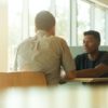 two men talking at a table by linkedin sales solutions