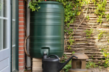 Water butt in garden with watering can