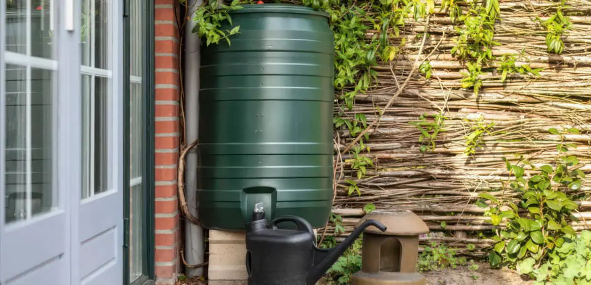 Water butt in garden with watering can