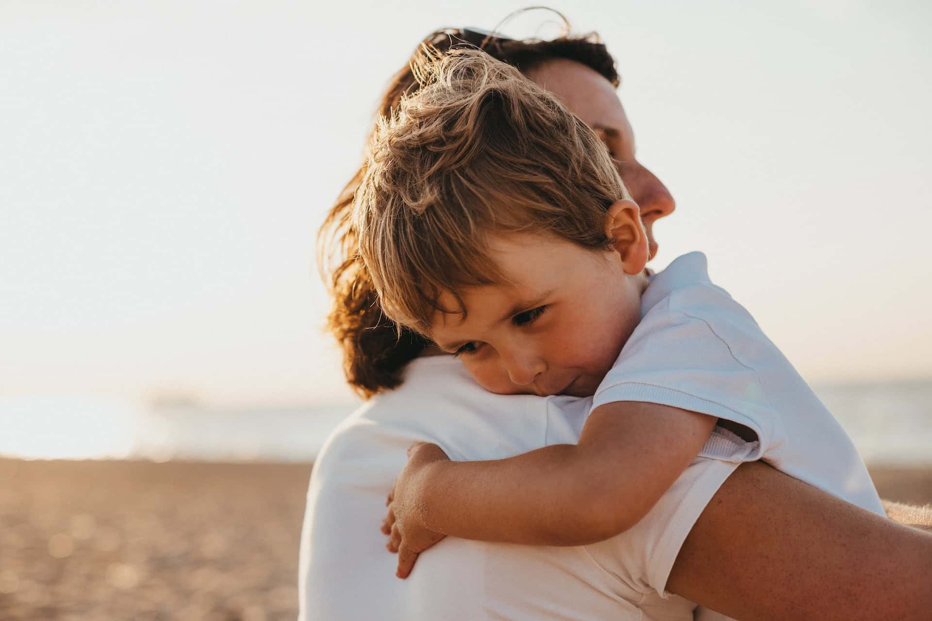 A toddler cuddling mother on the beach