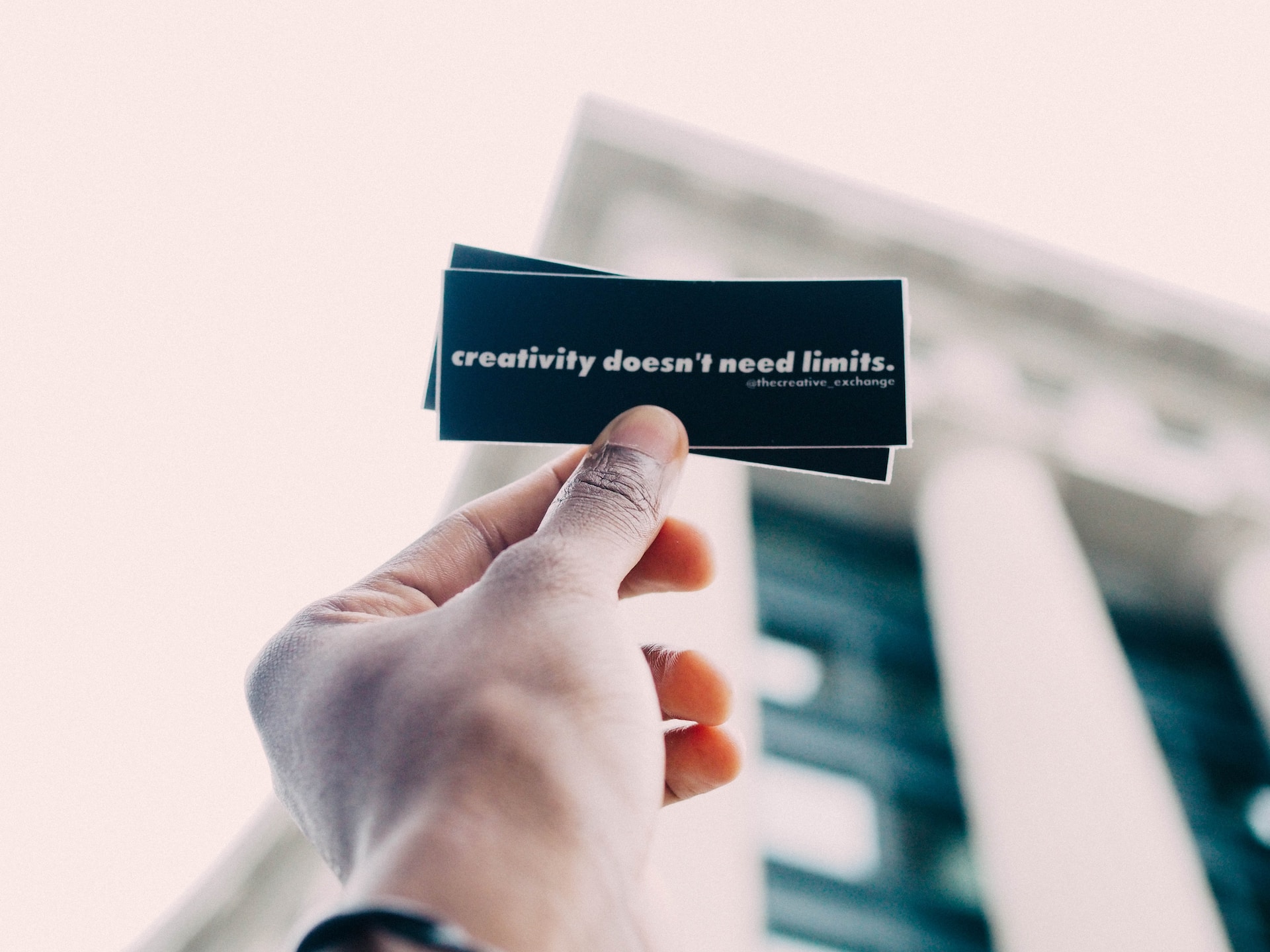 Person holding small card which says 'creativity doesn't need limits'